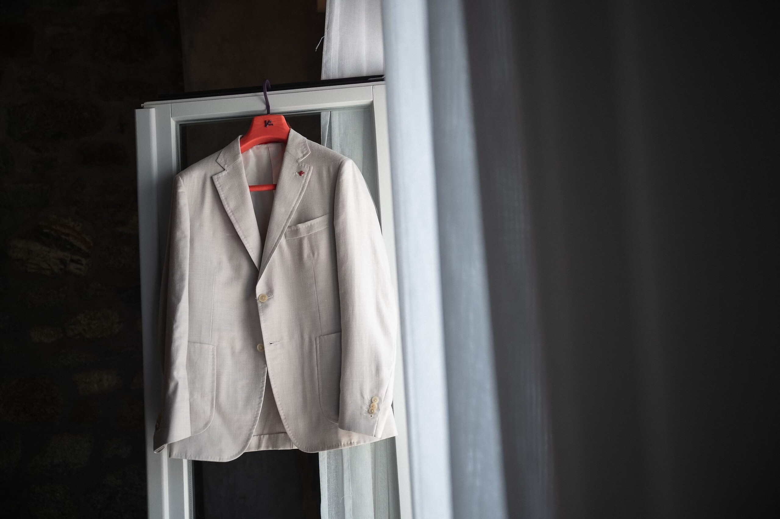 Justin’s light wedding suit hanging by a window before the Mykonos celebration