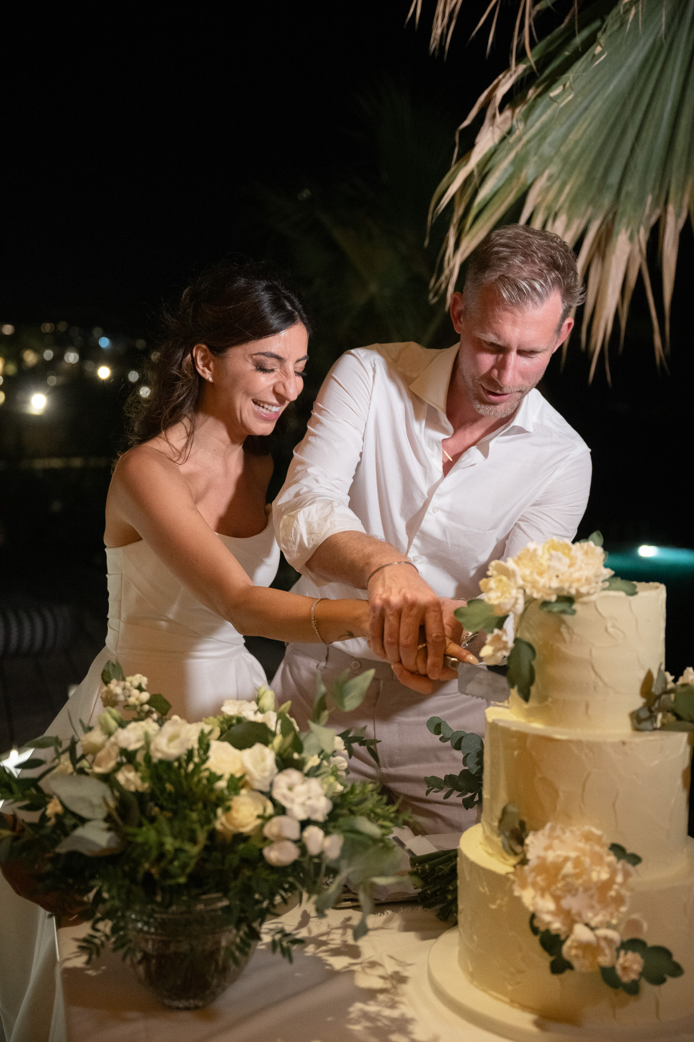 Martina and Justin cut their white floral wedding cake together at the reception.