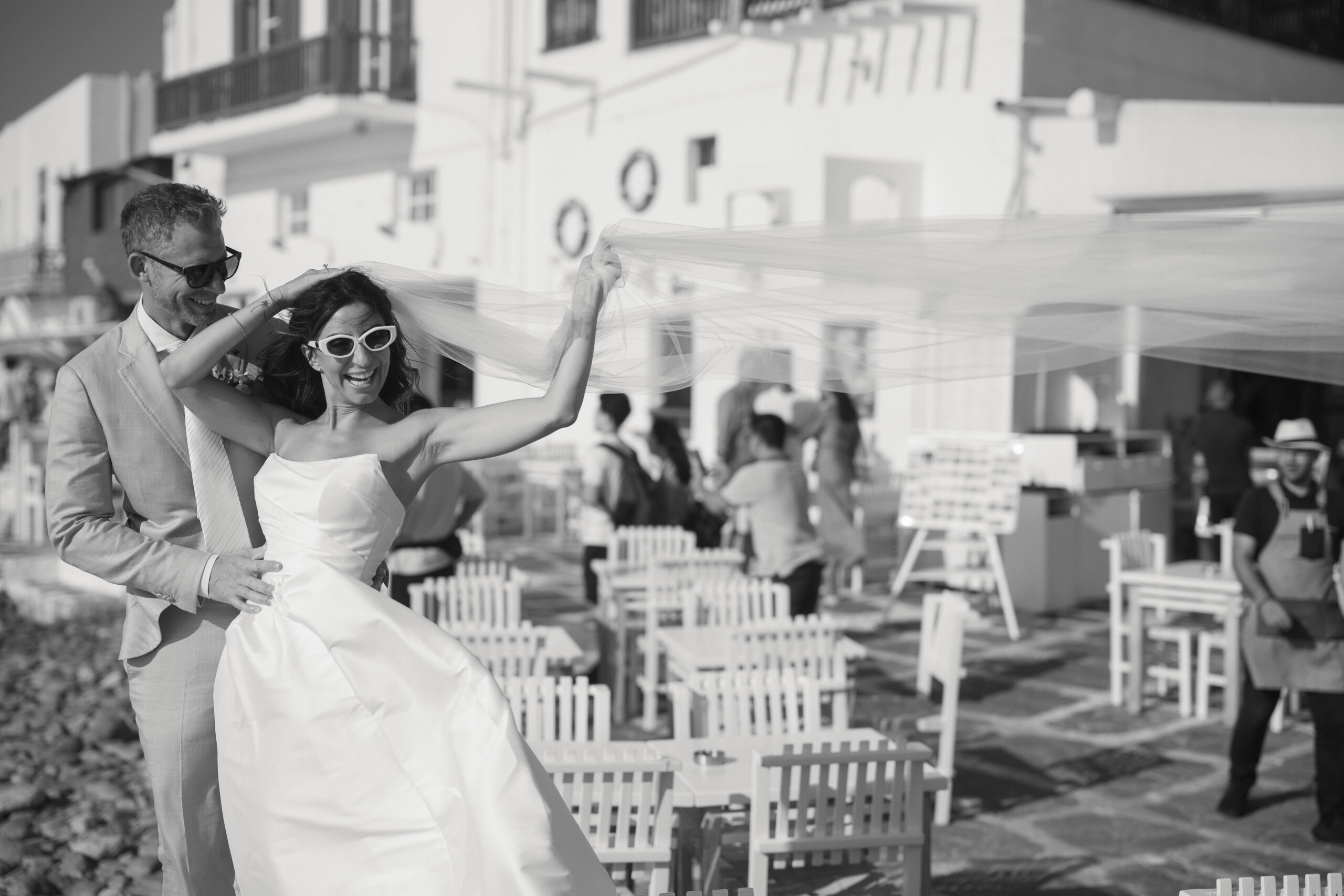 Justin and Martina laughing together as she lifts her veil during their Mykonos wedding.