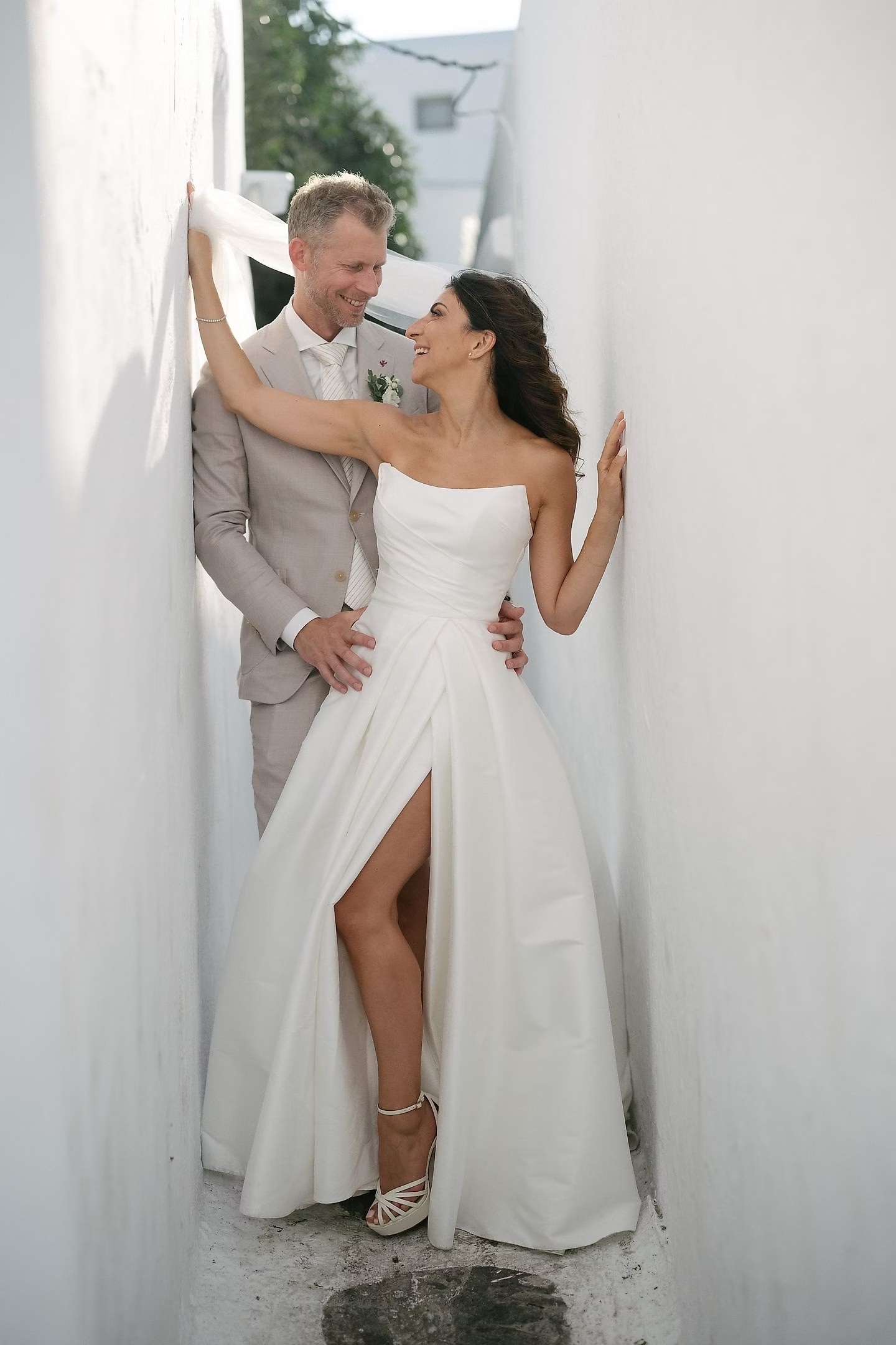Martina and Justin sharing a relaxed portrait against pale island architecture