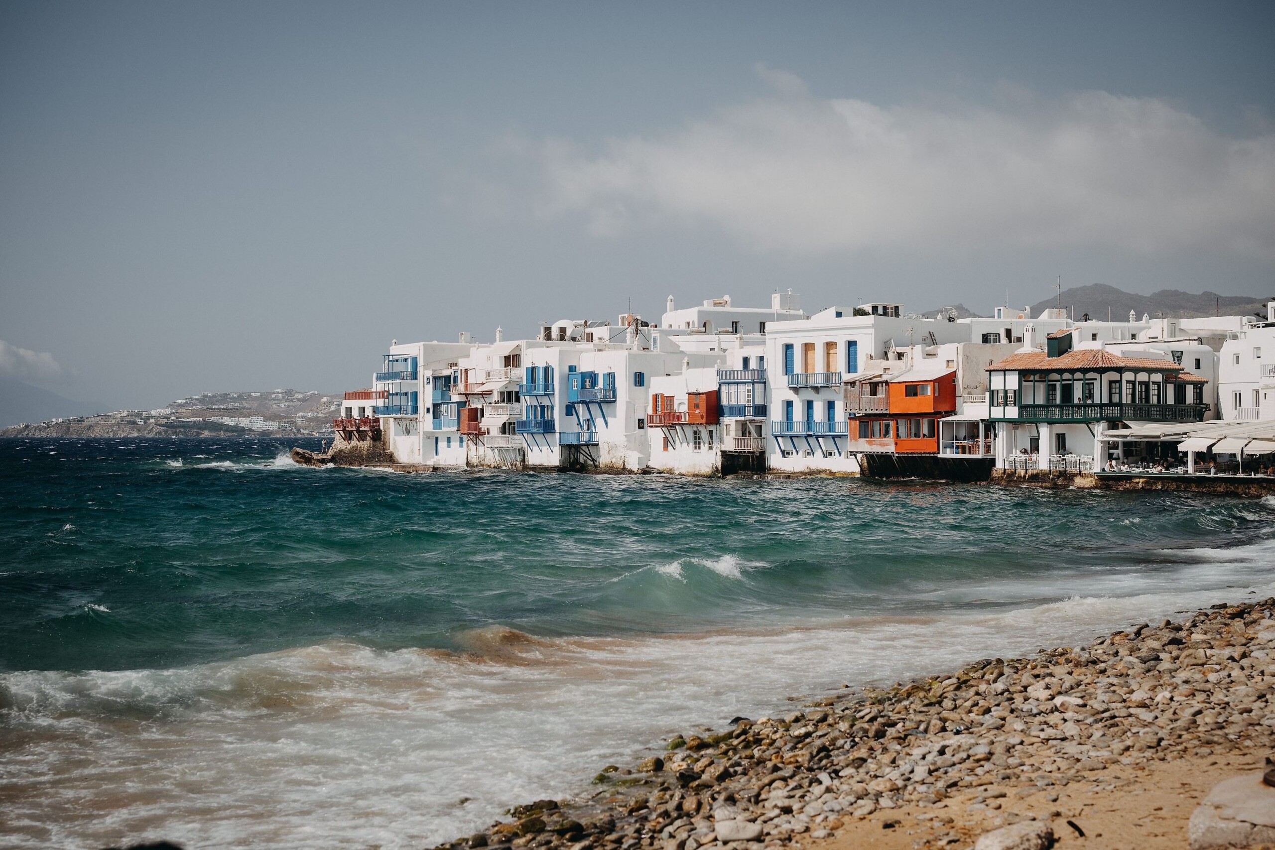 White waterfront buildings beside the Aegean shoreline in Mykonos