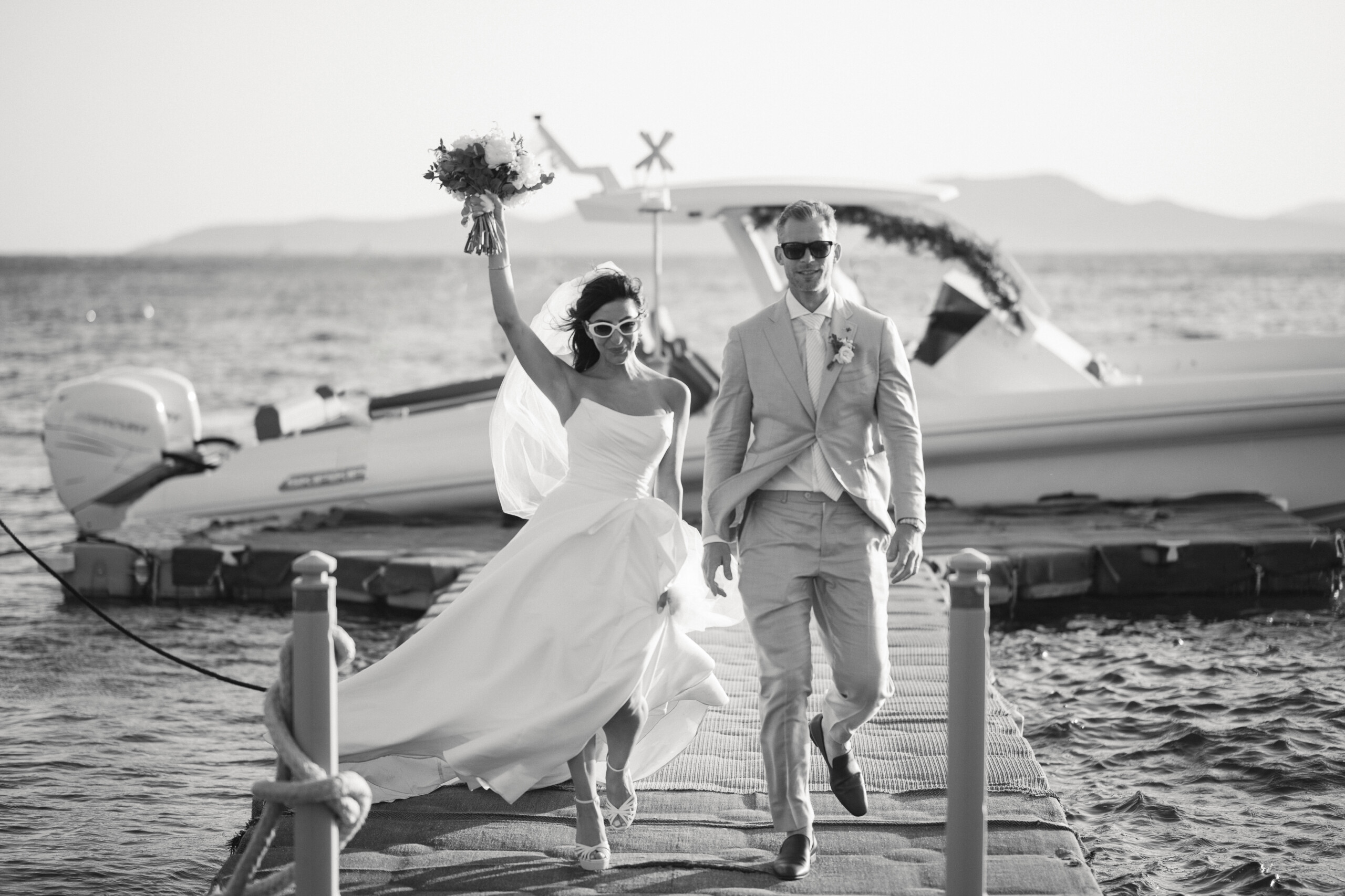 Martina and Justin walking together along a dock beside the Aegean during their Mykonos wedding