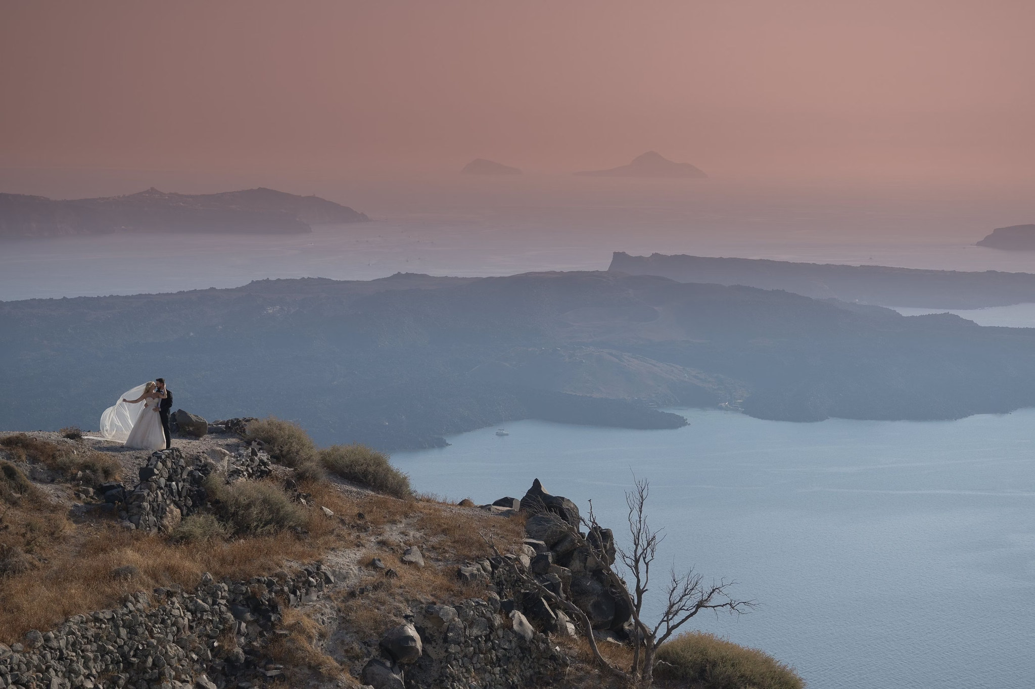 Margi and Nikos photographed against Santorini’s broad caldera landscape